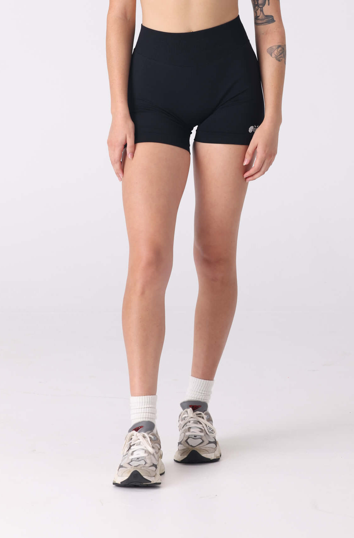 Woman wearing a black sports bra and shorts on a white background