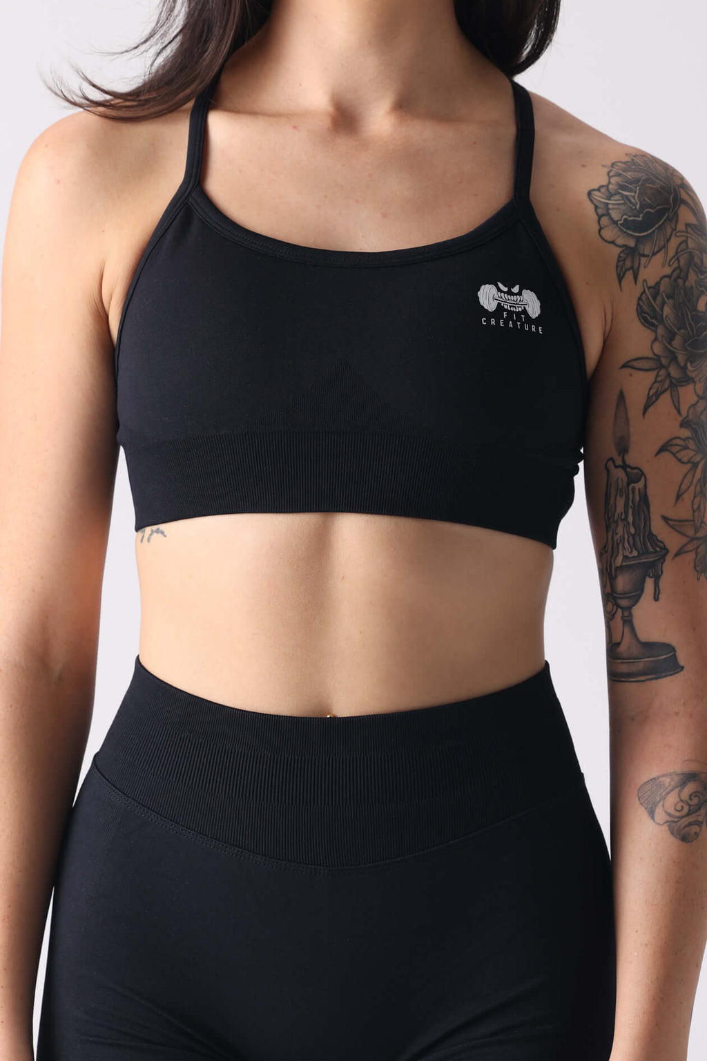 Person wearing a black sports bra and shorts set on a white background