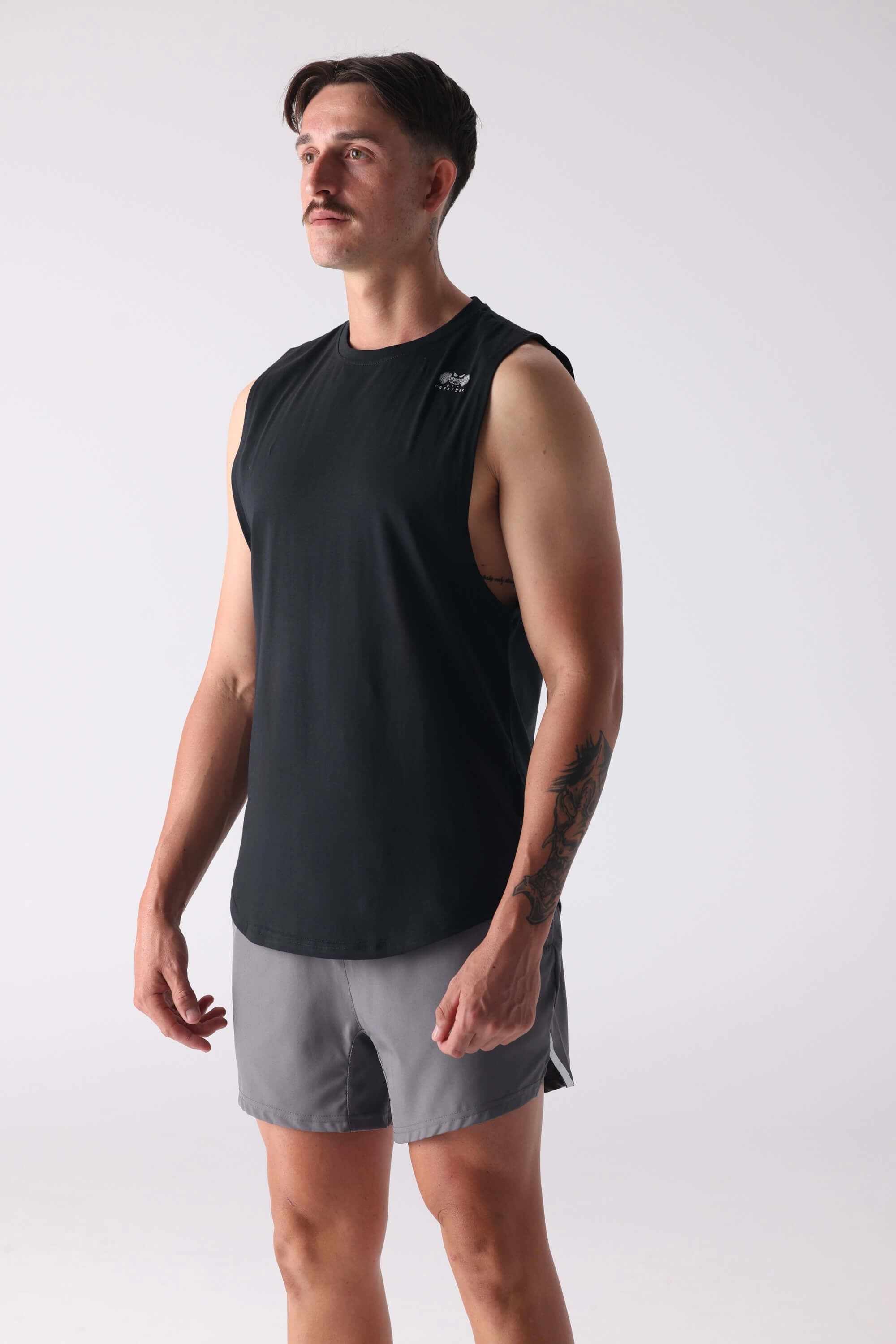 Man wearing a black sleeveless shirt and gray shorts on a white background
