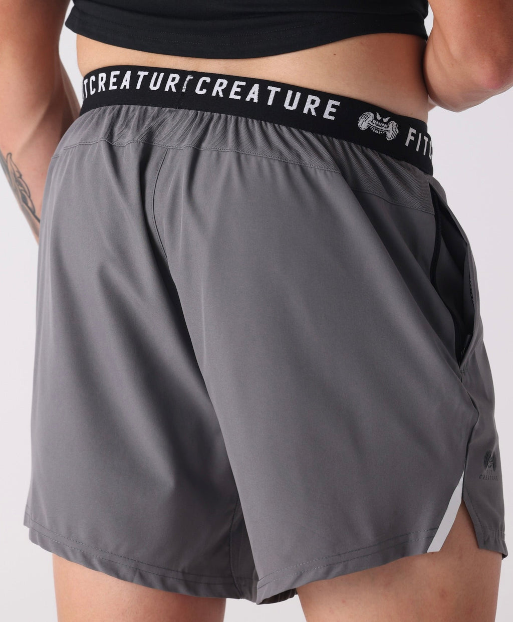 man wearing gray shorts with a visible brand logo on a white background