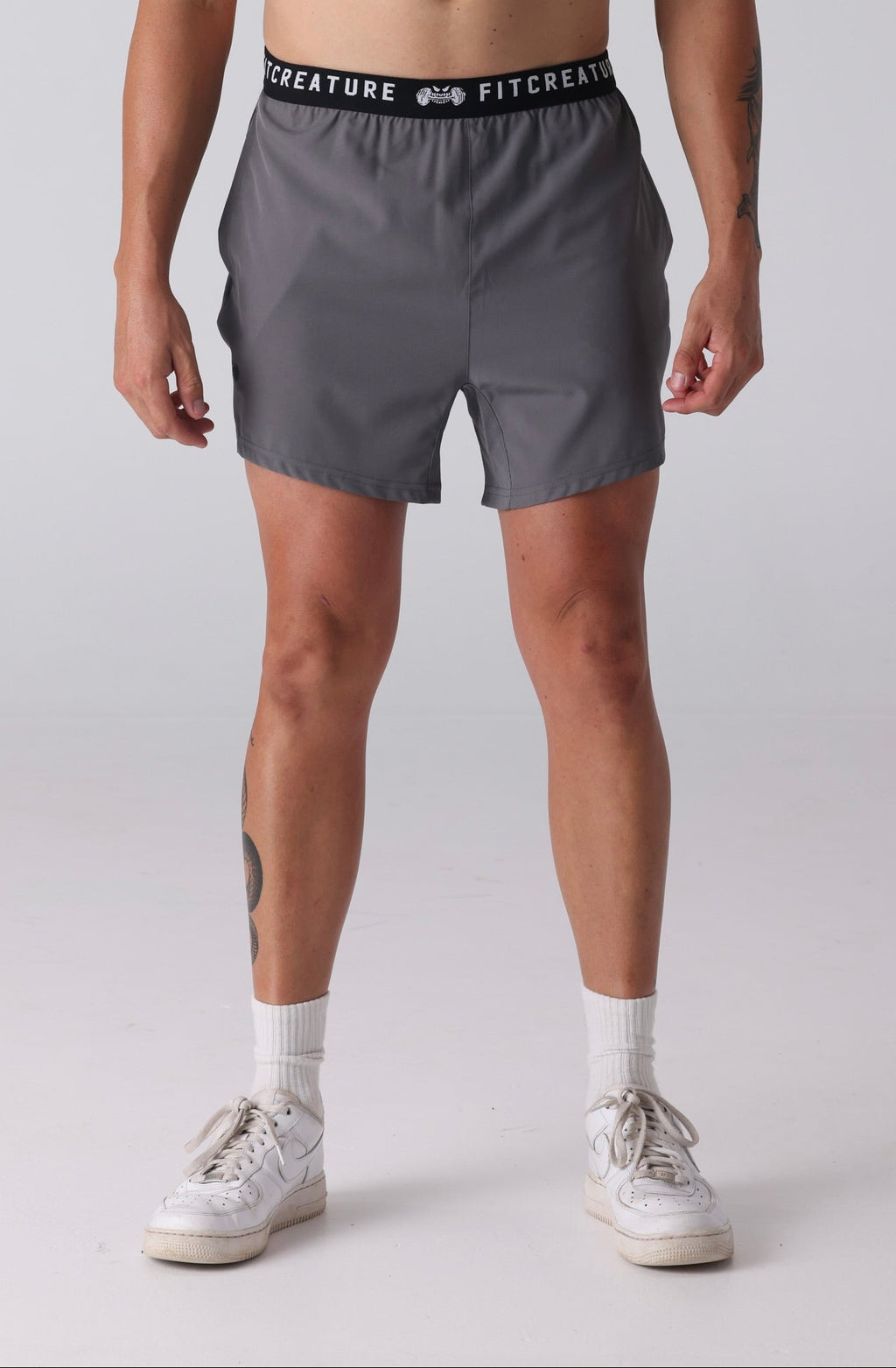 Man wearing a black sleeveless shirt and gray shorts on a white background