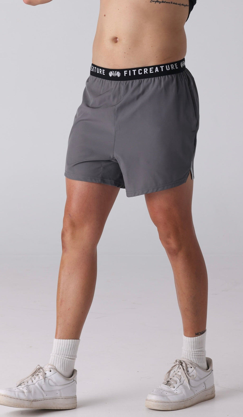 Man wearing gray athletic shorts with a visible brand logo on a white background