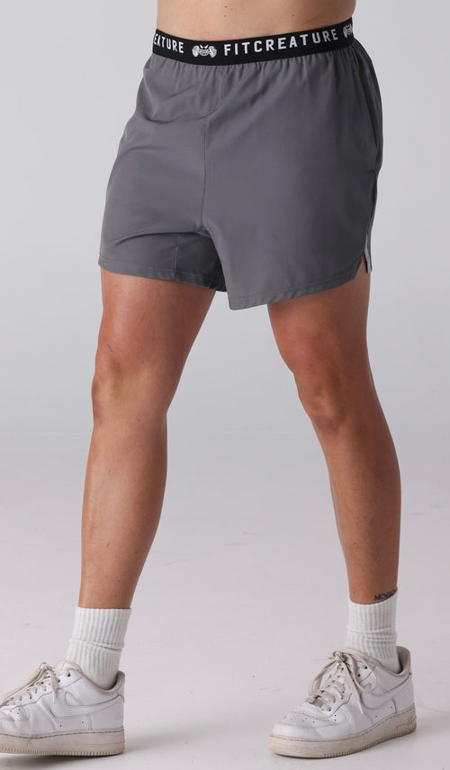 Man wearing gray athletic shorts with a visible brand logo on a white background