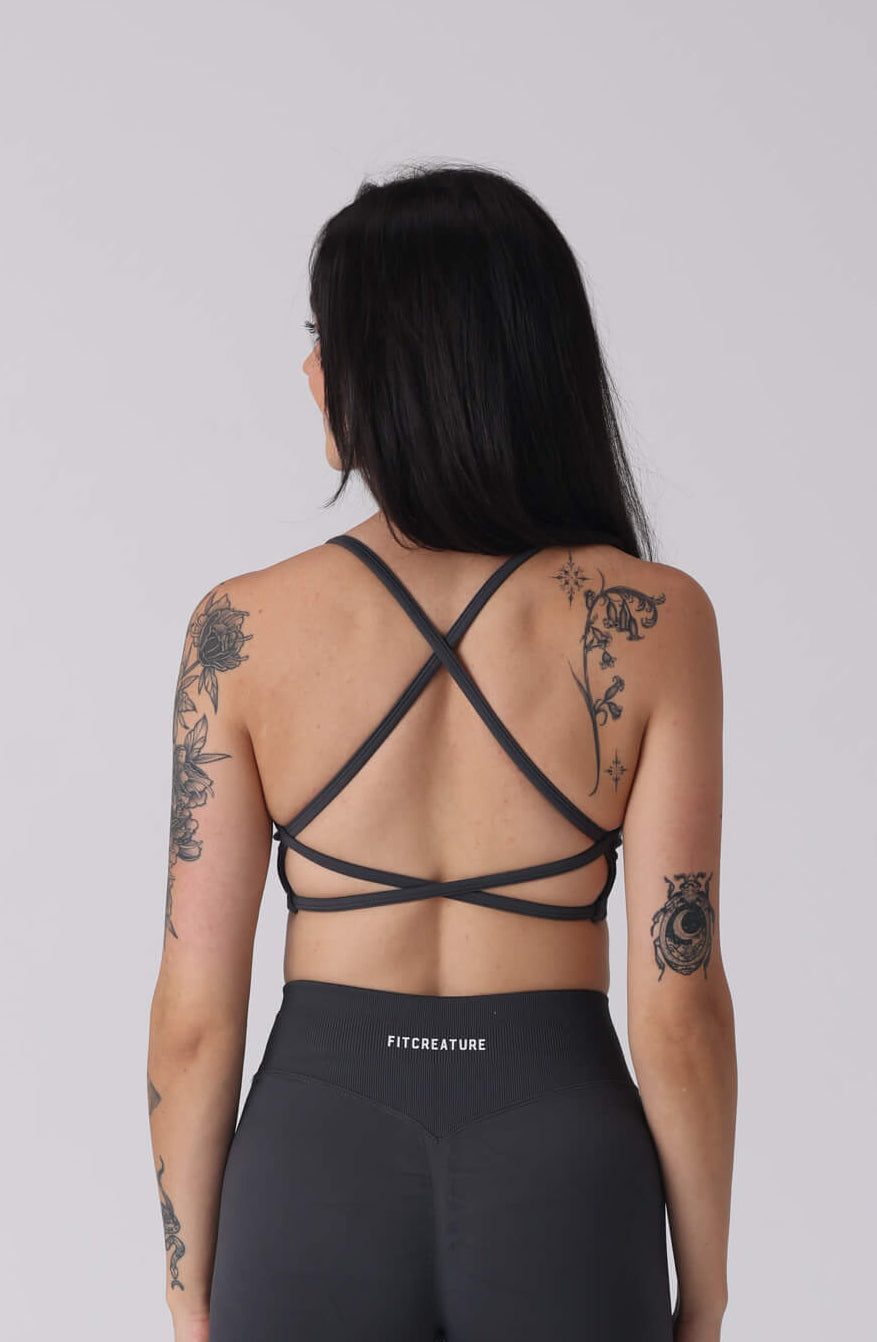 Person wearing a black strappy top and shorts on a white background