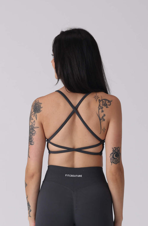 Person wearing a black strappy top and shorts on a white background