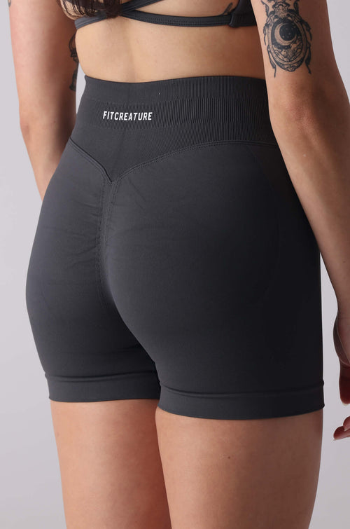 Person wearing black athletic shorts with 'FYTCH' branding on a plain background